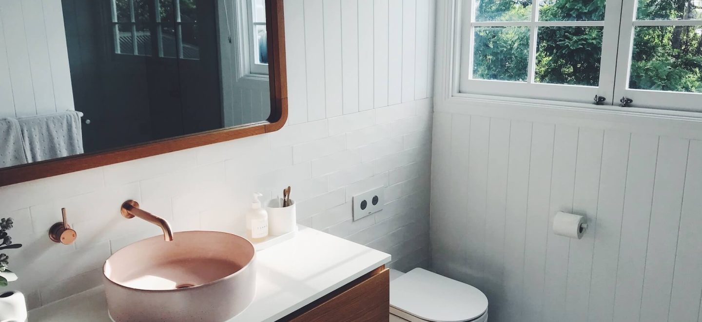 Dark brown sink, rimmed mirror and cabinet in a white bathroom - K4 Kitchens Trowbridge